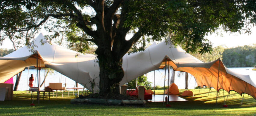 white stretch tent by lake outdoors under tree, dancefloor, full customisation creating stylish peaks and sexy contours.